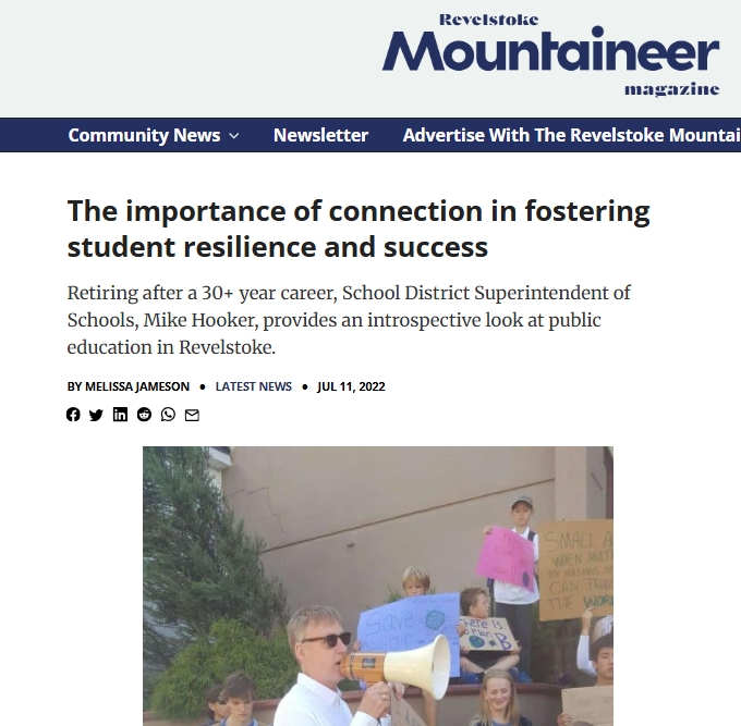 Person using a megaphone in front of a small crowd of seated and standing people holding handmade signs on building steps; site masthead at top reads "Revelstoke Mountaineer." Article headline visible: "The importance of connection in fostering student resilience and success." Byline "By Melissa Jameson" and date "Jul 11, 2022."